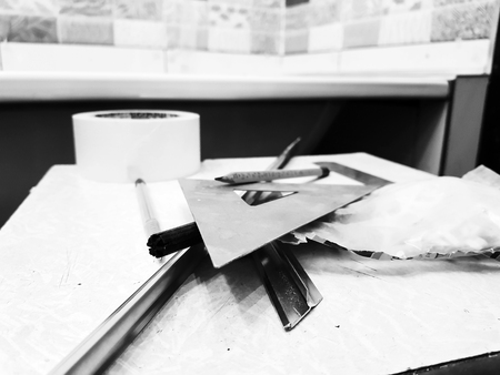 Repair - building with tools, tape measure, pencil, pen, marker, masking tape, triangle, corner, tile corners, aluminum, masking tape on the tiled floorの写真素材