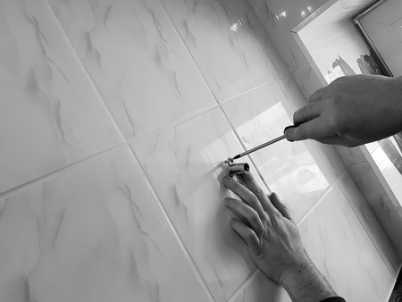 Construction and repair - a professional tool and screwdriver in the hands of the builder-plumberの写真素材