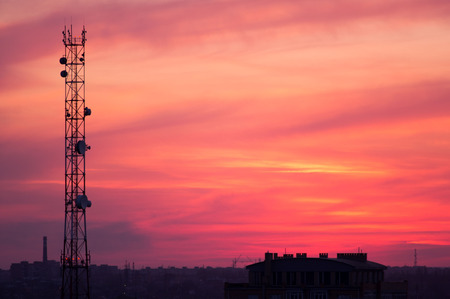 Cell tower and city buildings at sunsetの写真素材