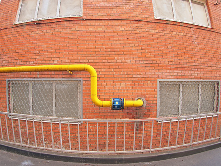 Wall of a building with a yellow gas pipe and windows with wide angle fisheyeの写真素材