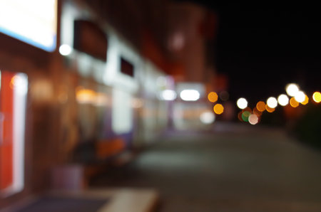 Night urban scene with diffuse lighting shop windows and lanterns on the street for use as a background.の写真素材