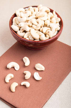 Raw cashew nuts for vegetarian food in a wooden bowl on the tablecloth close-upの写真素材