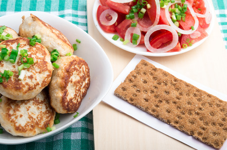 Top view of a dining table with homemade rissole with a salad of raw tomato on a green tableclothの写真素材