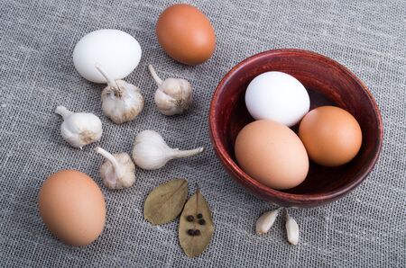 Top view of a chicken egg and garlic and spices on the kitchen table on old textile backgroundの写真素材
