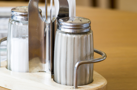 Glass containers on the table in a cafe with salt and pepper closeup with shallow depth of field and selective focusの写真素材