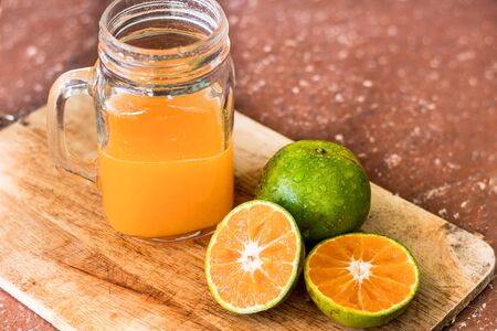 Orange juice in glass and oranges on a wooden board.の写真素材