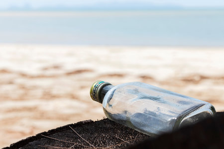 Empty used dirty glass bottles on the seaside. Ecological problem and environmental pollution. Glass...