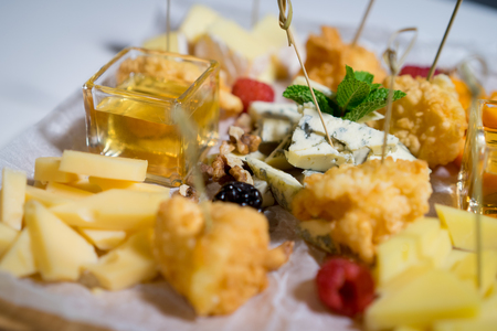 Male hand cuts and takes a piece of cheese with  beautiful table  snacksの写真素材