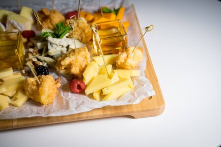 Male hand cuts and takes a piece of cheese with  beautiful table  snacksの写真素材