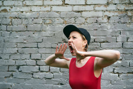 the girl in the red cries on a background of gray brick wallの写真素材