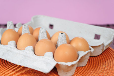 Fresh brown eggs with yolk on cardboard tray