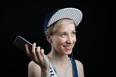 girl in baseball cap listening to music on black background