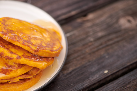 Homemade pancakes with honey and walnuts, white plate, dipper, dark wooden table.の写真素材