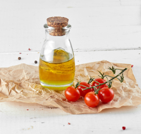 tomatoes with oil bottle on white wooden backgroundの写真素材