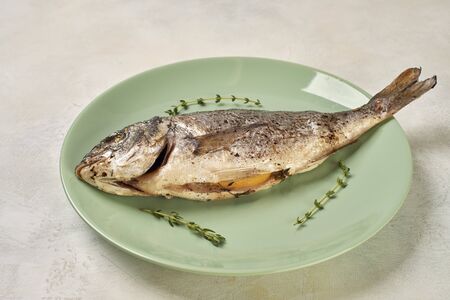 baked Dorado fish on a green plateの写真素材