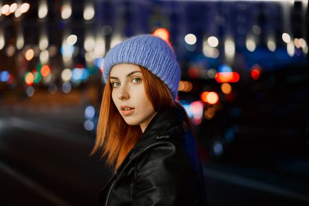 beautiful red-haired girl in blue hat at nightの写真素材