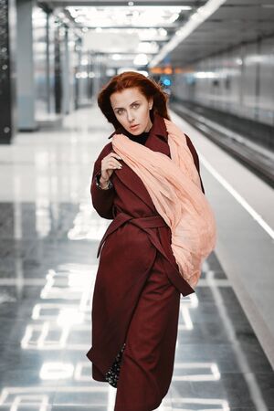 Red-haired girl in the subway, red coatの写真素材
