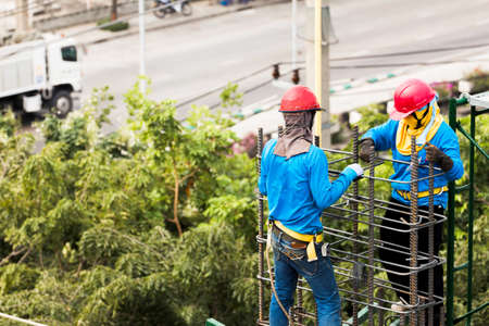 worker installing steel column on scaffolding in construction siteの写真素材