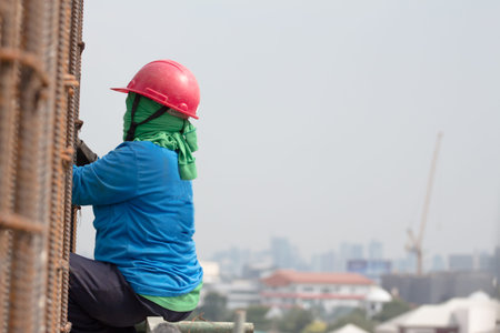 worker installing steel column on scaffolding in construction site