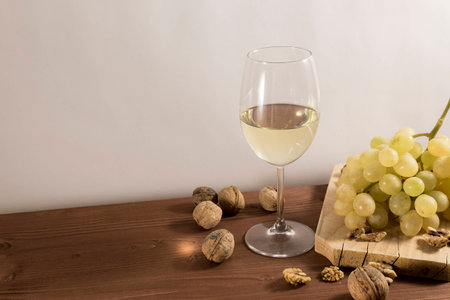 Grape with walnuts and a glass of white wine in wooden rustic tableの写真素材