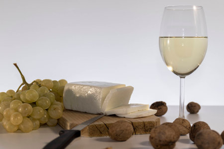 Chees, grapes, wallnuts and a glss of white wine on rustic wooden tableの写真素材