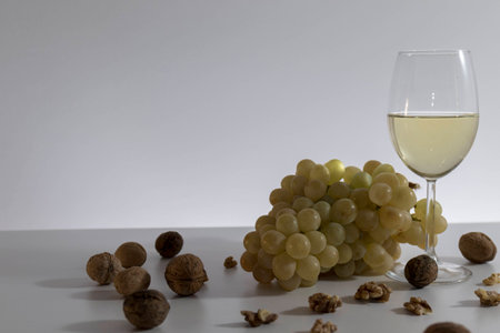 Grapes, wallnuts and a glss of white wine on rustic wooden tableの写真素材