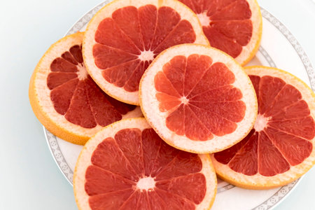 Grapefruit juicy and healthy slices on white surfaceの写真素材