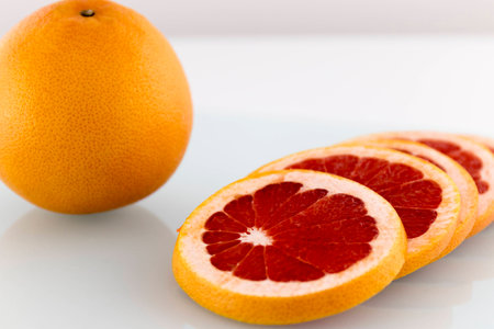 Grapefruit juicy and healthy slices on white surfaceの写真素材
