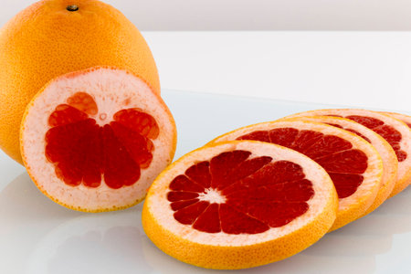 Grapefruit juicy and healthy slices on white surfaceの写真素材
