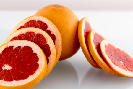 Grapefruit juicy and healthy slices on white surfaceの写真素材