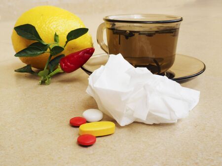 Hot tea for colds, pills and handkerchiefs on table,lemon and peppers, natural remedyの写真素材