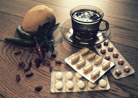 Hot tea for colds, pills and handkerchiefs on table,lemon and peppers, natural remedyの写真素材