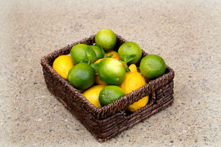 Lemons and limes in brown basketの写真素材