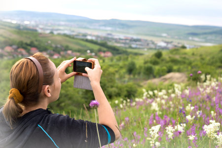 woman using a smartphone photographing flowers