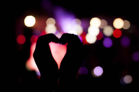 silhouettes of concert crowd in front of bright stage lightsの写真素材