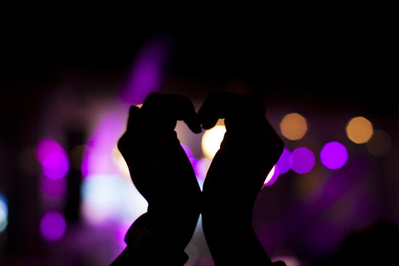 silhouettes of concert crowd in front of bright stage lightsの写真素材