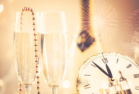 New Year champagne glasses with fireworks and clockの写真素材