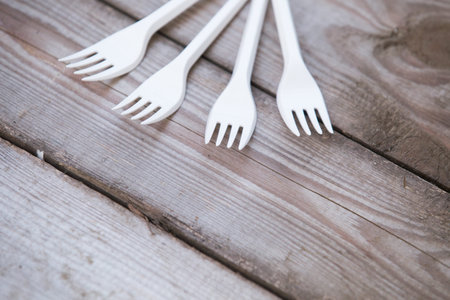 Plastic white forks on wooden background plastic free concept