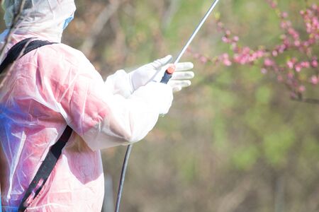 Coronavirus disinfection. Worker in hazmat making disinfection in public parkの写真素材
