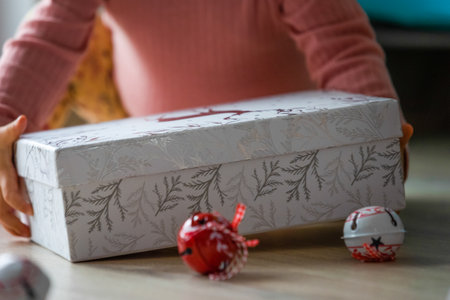 Close up of pregnant woman packing christmas gift box in living roomの写真素材