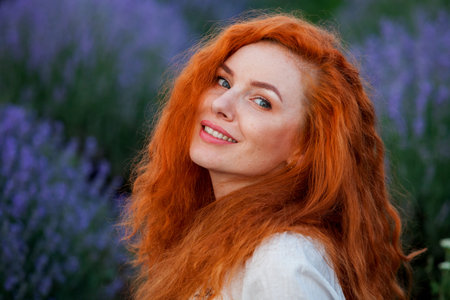 Summer portrait of a beautiful girl with long curly red hair. woman with long hair. European girl in...