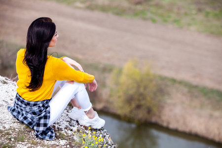 A young traveler girl sit on the top of valley. Young girl love wild life, travel, freedom. Woman Enjoying Nature.の写真素材