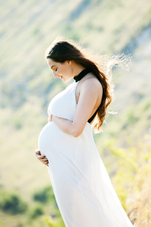 Pregnant woman with long healthy hair and flowers. Beautiful girl waiting for the baby. Future...