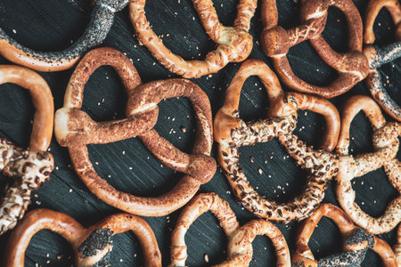 Fresh prepared homemade soft pretzels. Different types of baked pretzels with seeds on a black...