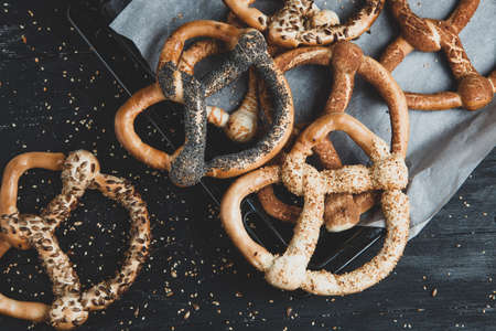 Fresh prepared homemade soft pretzels. Different types of baked pretzels with seeds on a black backgroundの写真素材