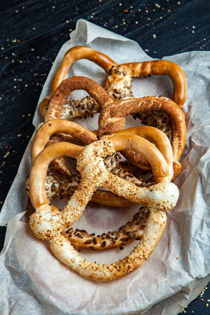 Fresh prepared homemade soft pretzels. Different types of baked bagels with seeds on a black background.の写真素材