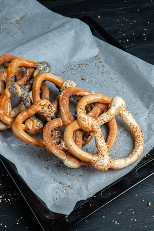 Fresh prepared homemade soft pretzels. Different types of baked bagels with seeds on a black...