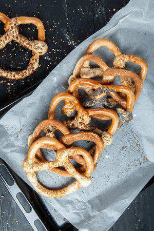 Fresh prepared homemade soft pretzels. Different types of baked bagels with seeds on a black...
