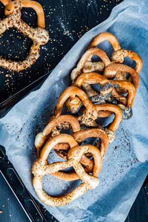 Fresh prepared homemade soft pretzels. Different types of baked bagels with seeds on a black...