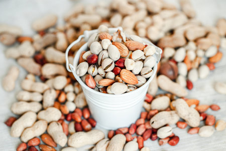 Mix of nuts in a bucket on a white wooden background. Selective focus.の写真素材